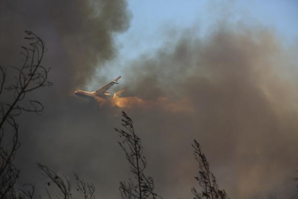 A firefighting aircraft drops water on a wildfire near the town of Manavgat