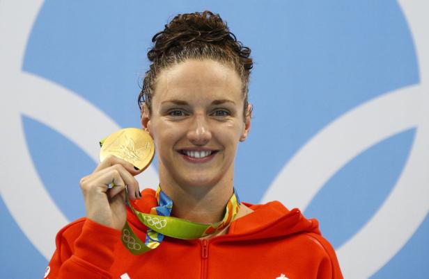 Swimming - Women's 200m Individual Medley Victory Eine Schwimmerin hält stolz ihre Goldmedaille in der Hand.