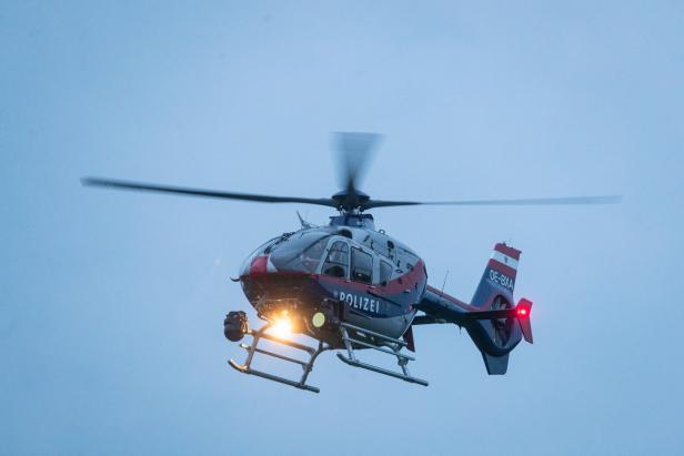 Ein rot-blau-weisser Polizei-Hubschrauber mit der Kennung OE-BXA ist in der Luft.