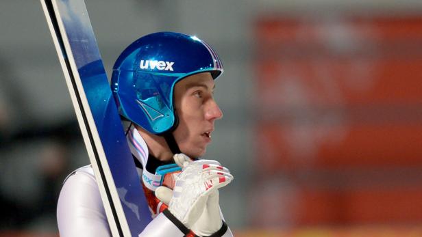 Ein Skispringer mit blauem Helm und Skiern wartet auf seinen Einsatz.