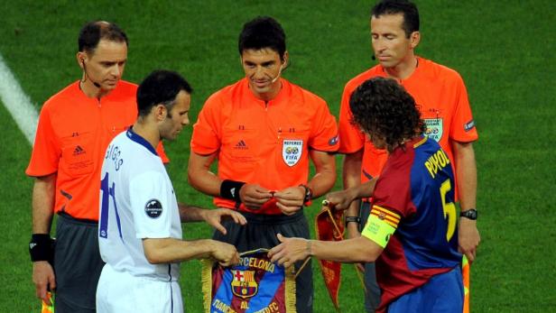 Ryan Giggs und Carles Puyol tauschen vor einem Fußballspiel eine Wimpel aus, umgeben von Schiedsrichtern.