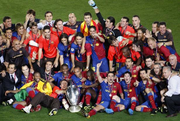 Die Fußballmannschaft des FC Barcelona feiert mit der Trophäe auf dem Rasen.