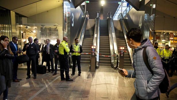 Mehrere Personen stehen vor gesperrten Rolltreppen in einem Bahnhof.