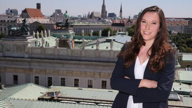 Eine Frau steht vor der Wiener Skyline mit Hofburg und Stephansdom im Hintergrund.