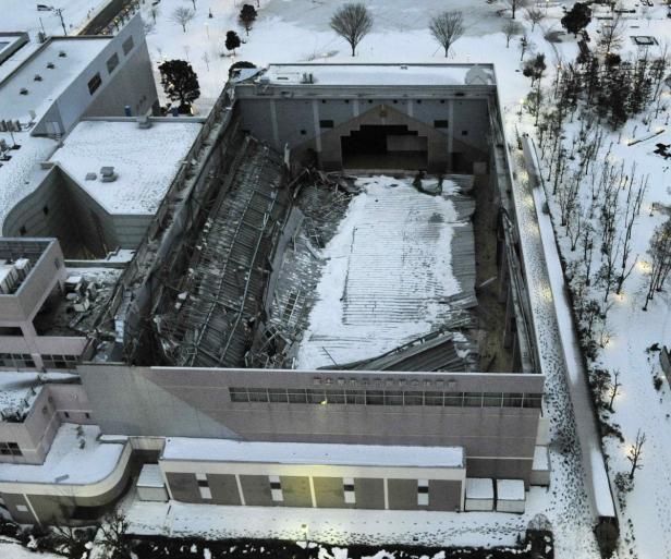 Ein beschädigtes Gebäude mit eingestürztem Dach unter einer Schneedecke.