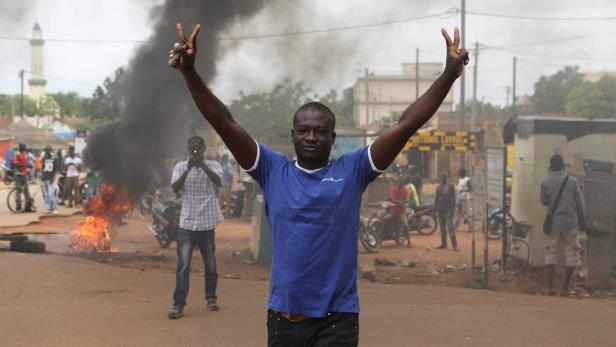 A protester gestures in front of a burning roadblo Putschisten in Burkina Faso übernehmen Regierung