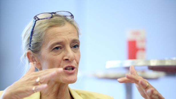Eine Frau mit Brille gestikuliert während eines Gesprächs.