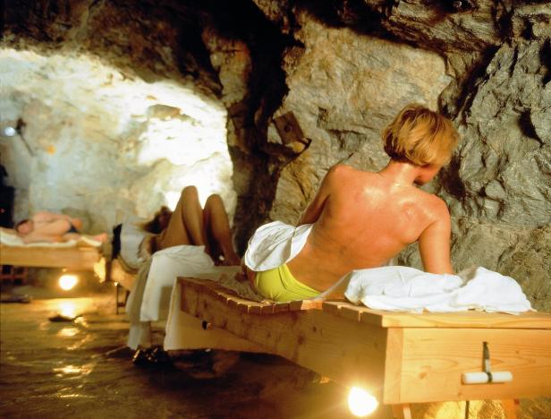 Mehrere Personen entspannen sich auf Liegen in einer Grotte.