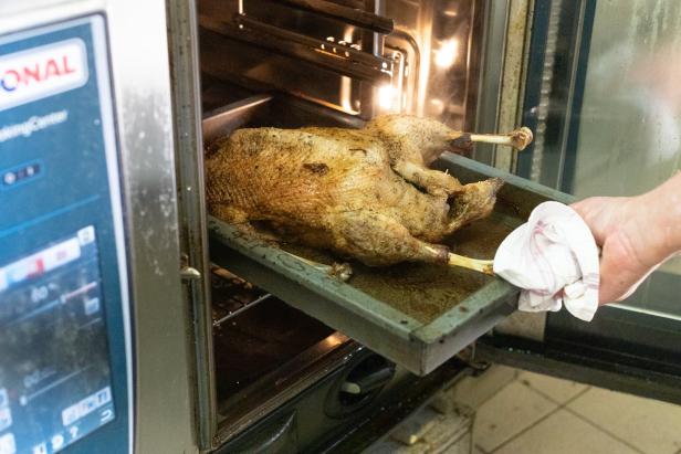 Eine gebratene Gans wird aus einem Ofen genommen.