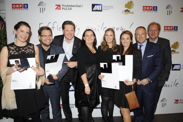 Eine Gruppe von Personen posiert mit „Platin Effie 2013“-Auszeichnungen vor einer Wand mit Logos.