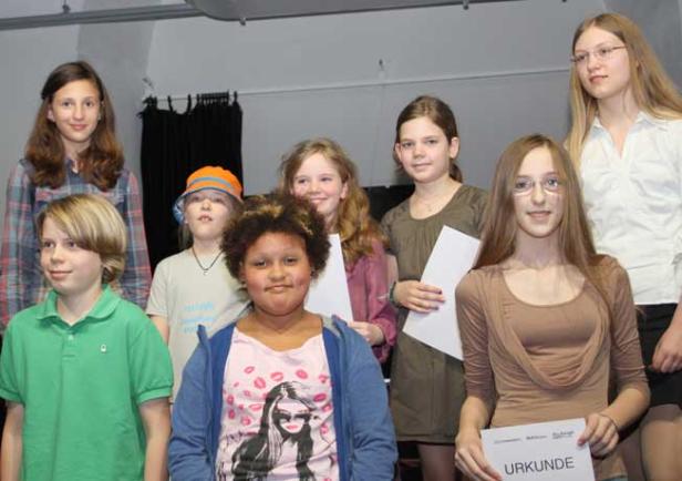 Eine Gruppe von Kindern steht zusammen, einige halten Urkunden in den Händen.