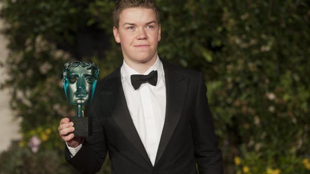 Will Poulter hält eine BAFTA-Trophäe in der Hand.