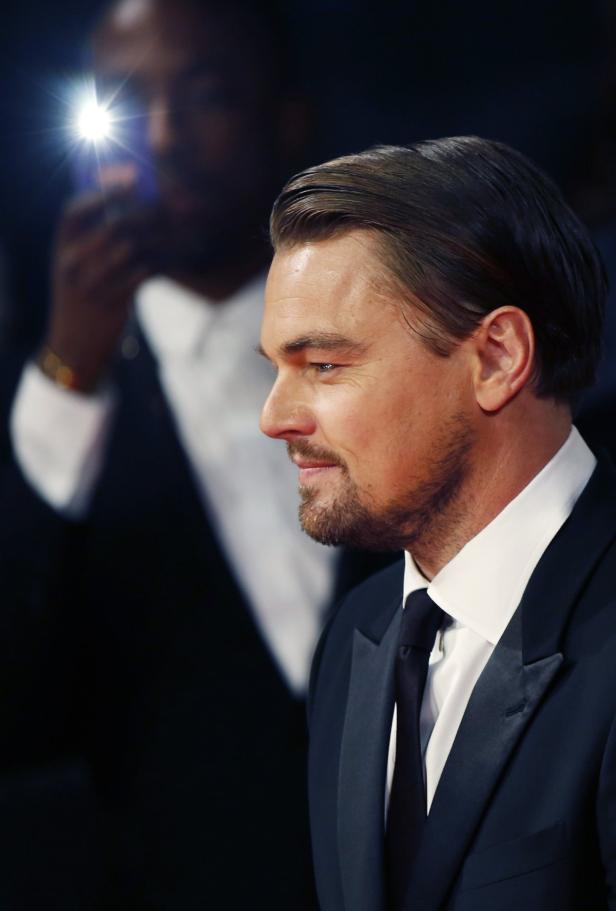 Leonardo DiCaprio im Profil, im Hintergrund ein Fotograf mit Blitz.