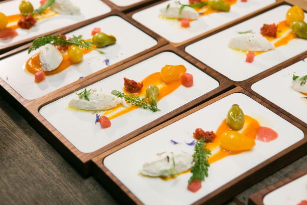 Mehrere Teller mit einer Vorspeise aus Käse, Tomaten und Kräutern werden serviert.