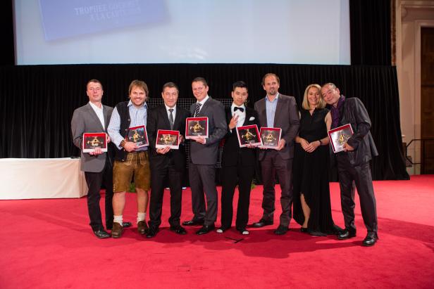 Eine Gruppe von Personen posiert mit Auszeichnungen auf einem roten Teppich.