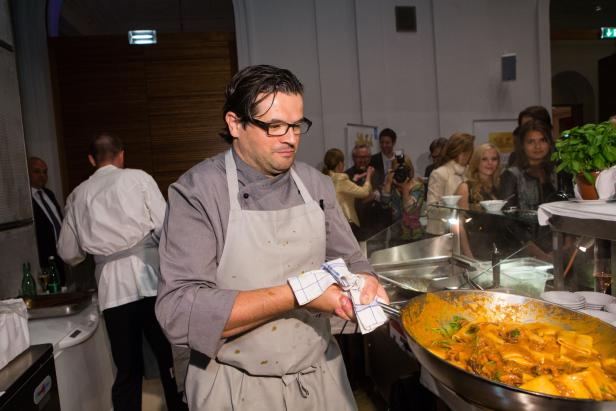 Ein Koch bereitet in einer großen Pfanne Pasta zu.