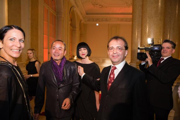 Eine Gruppe von Menschen posiert in einem eleganten Saal für ein Kamerateam.