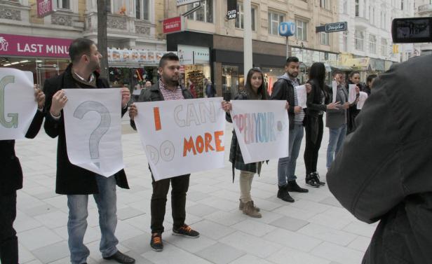 Eine Gruppe von Menschen hält Schilder mit den Aufschriften „I CAN DO MORE“ und „OPEN YOUR EYES“.
