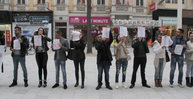 Eine Gruppe von Menschen hält Schilder hoch, die zusammen das Wort „STOP RACISM“ ergeben.