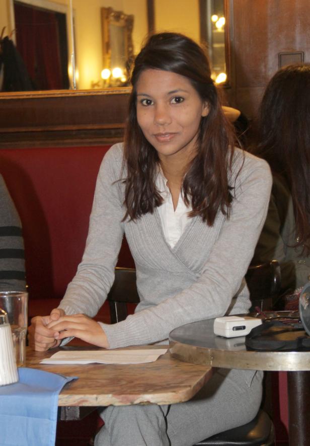 Eine junge Frau sitzt an einem Tisch in einem Café.