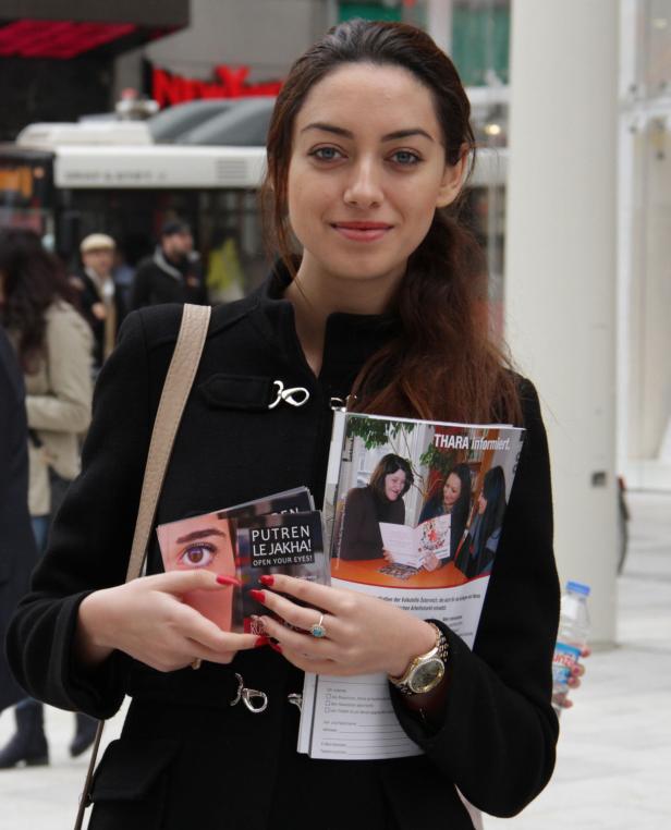 Eine Frau hält Flyer und Broschüren der Organisation THARA in der Hand.