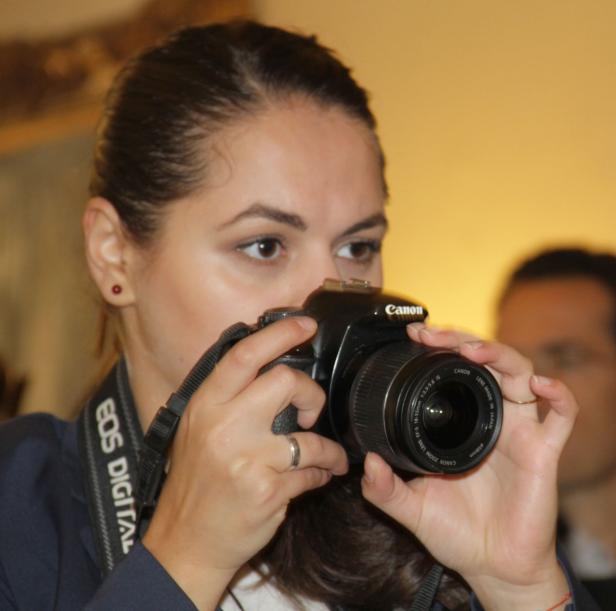 Eine Frau fotografiert mit einer Canon Spiegelreflexkamera.