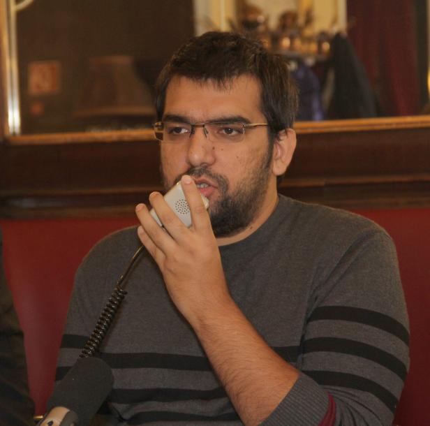 Ein Mann mit Brille spricht in ein Handmikrofon.