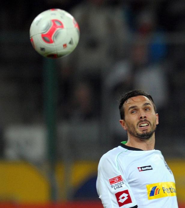 Ein Fußballspieler blickt auf einen fallenden Ball.