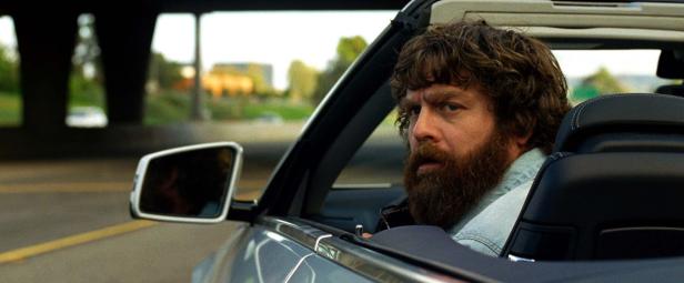 Zach Galifianakis fährt in einem grauen Cabriolet.