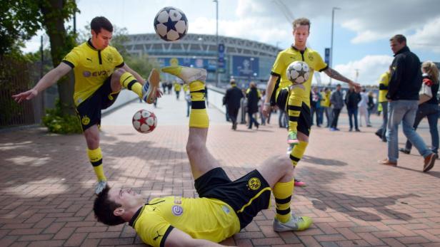 Drei Fußballspieler von Borussia Dortmund zeigen ihre Tricks vor dem Stadion.