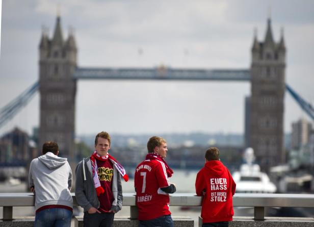 Vier junge Männer, einige in Bayern München Trikots, vor der Tower Bridge in London.