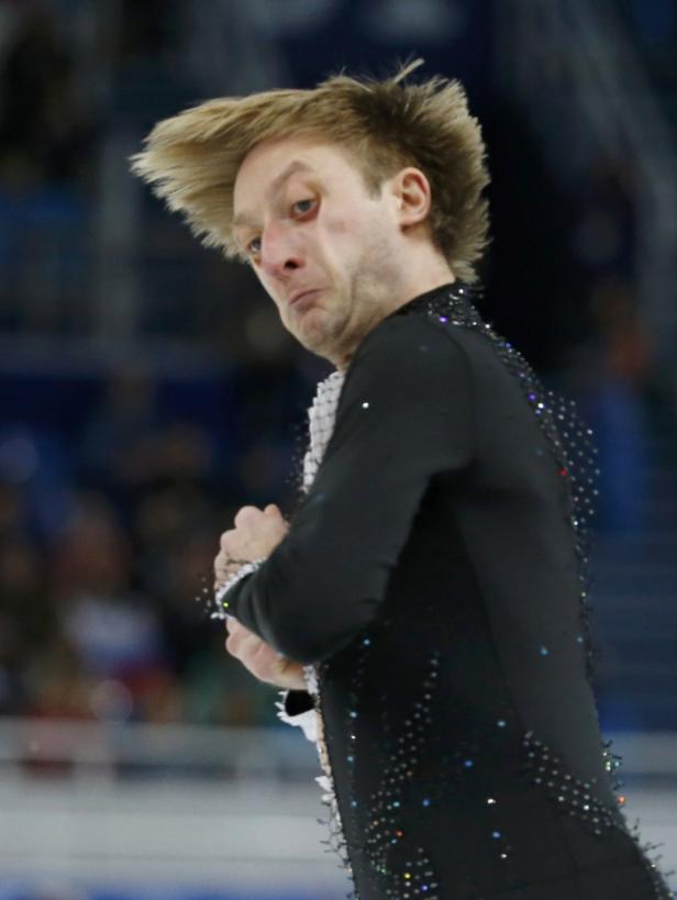 Ein Eiskunstläufer in einem schwarzen, glitzernden Kostüm macht eine Grimasse.