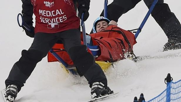Sanitäter transportieren eine verletzte Skifahrerin auf einer Trage durch den Schnee.