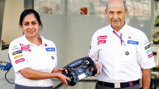 Eine Frau und ein Mann im Sauber F1 Team-Outfit präsentieren ein Formel-1-Lenkrad.