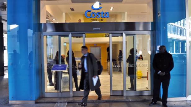 Ein Mann verlässt ein Büro von Costa Crociere, während ein Sicherheitsmann Wache hält.