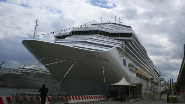 Die „Costa Fascinosa“ liegt im Hafen vor einem bewölkten Himmel.