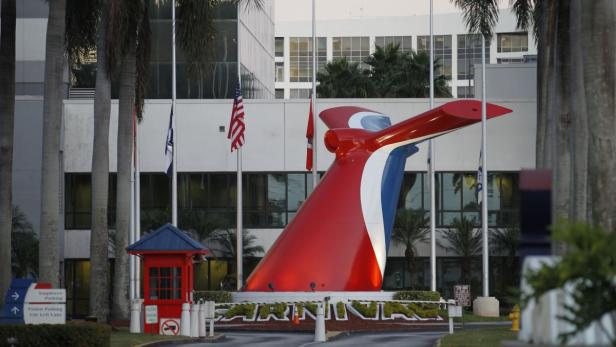 Das Heck eines Carnival-Kreuzfahrtschiffes steht vor dem Firmengebäude.