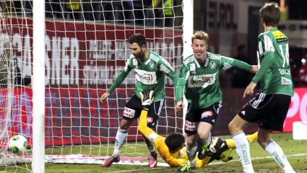 Fußballspieler jubeln, während der Torwart am Boden liegt und der Ball im Netz ist.
