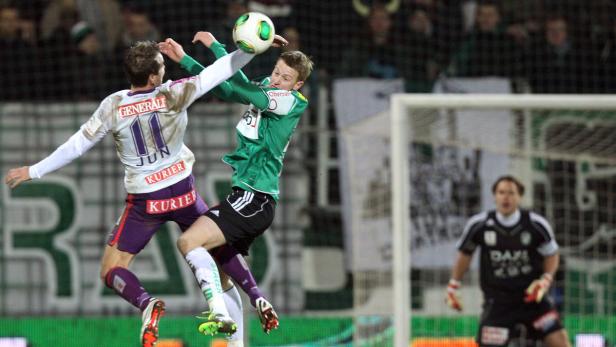 Zwei Fußballspieler kämpfen um den Ball vor dem Torwart.