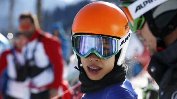 Eine Skifahrerin mit orangefarbenem Helm und Skibrille blickt zur Seite.