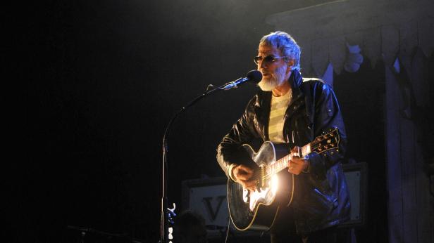 Ein Mann mit Bart und Sonnenbrille spielt Gitarre auf einer Bühne.