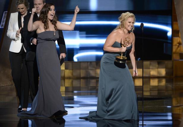 Amy Schumer hält einen Emmy Award auf der Bühne, während andere applaudieren.