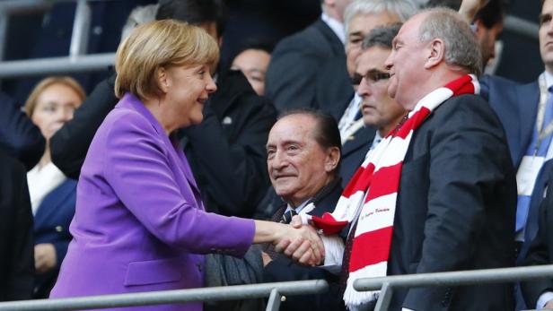 Hoeneß mit der Kanzlerin Angela Merkel schüttelt die Hand von Silvio Berlusconi, während Uli Hoeneß daneben steht.