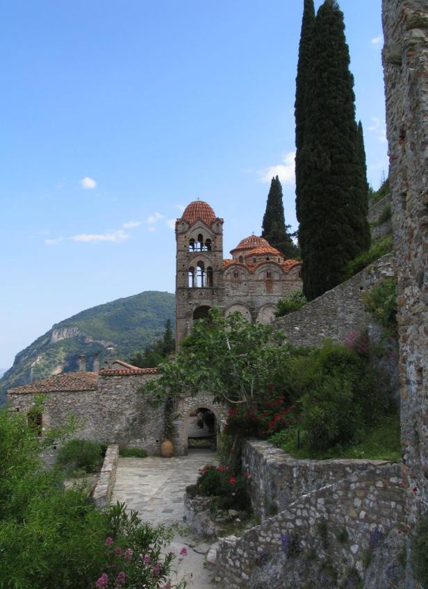 Eine alte Kirche mit roten Ziegeln und einem Turm steht auf einem Hügel.