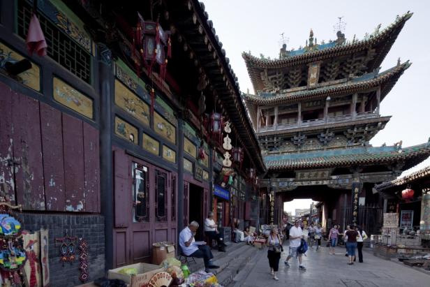 Eine belebte Straße in China mit traditioneller Architektur und einem mehrstöckigen Turm.