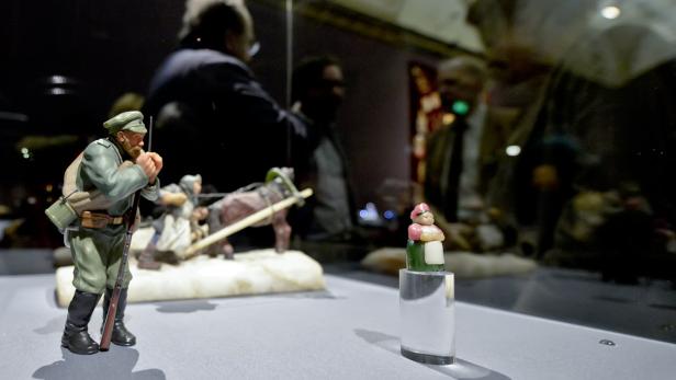 Eine Vitrine zeigt Miniaturfiguren, darunter einen Soldaten und eine Bäuerin.