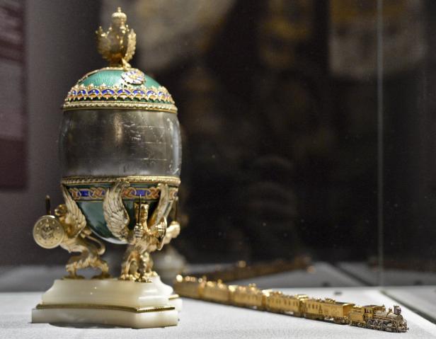 Ein Fabergé-Ei und ein Miniaturzug aus Gold stehen in einer Vitrine.