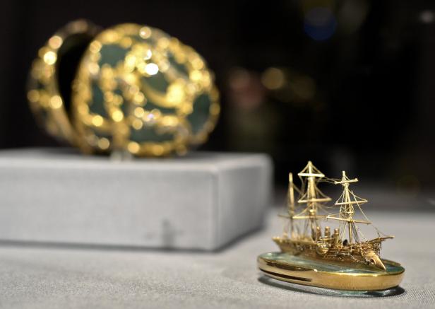 Ein goldenes Miniatur-Segelschiff und ein verziertes Schmuckei werden ausgestellt.