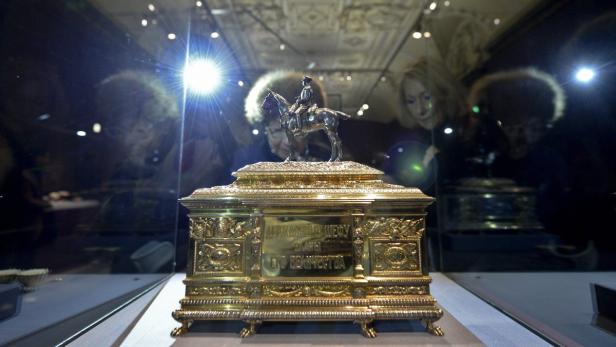 Ein vergoldetes Schmuckstück mit einer Reiterfigur in einer Vitrine.