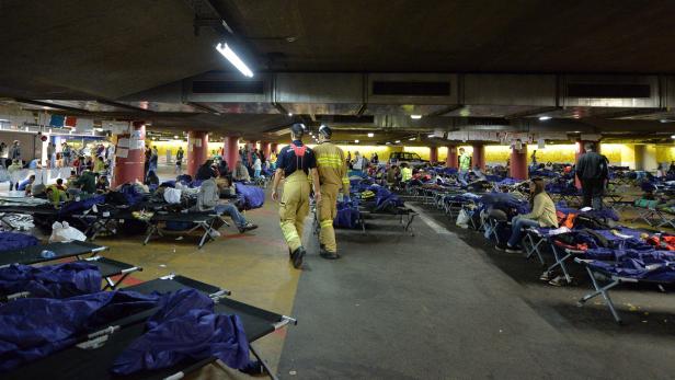 In einer Notunterkunft in einer Tiefgarage ruhen sich Menschen auf Feldbetten aus.